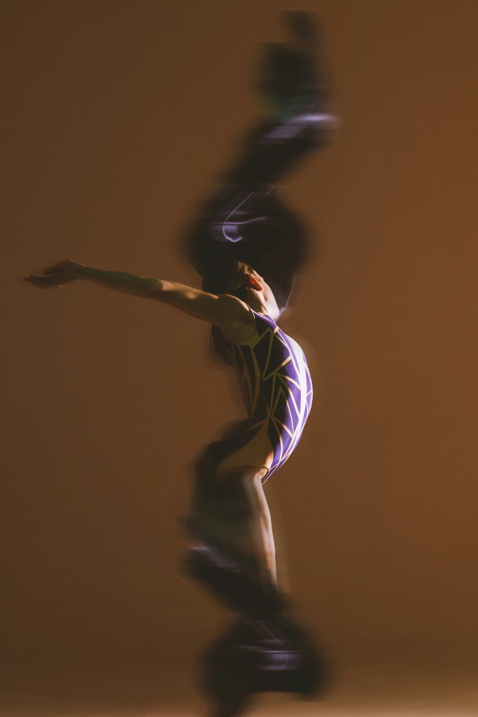 Blurry photo of a gymnast making dance moves - brown background
