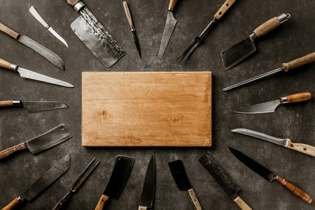 a-wooden-board-surrounded-by-knives-on-a-table