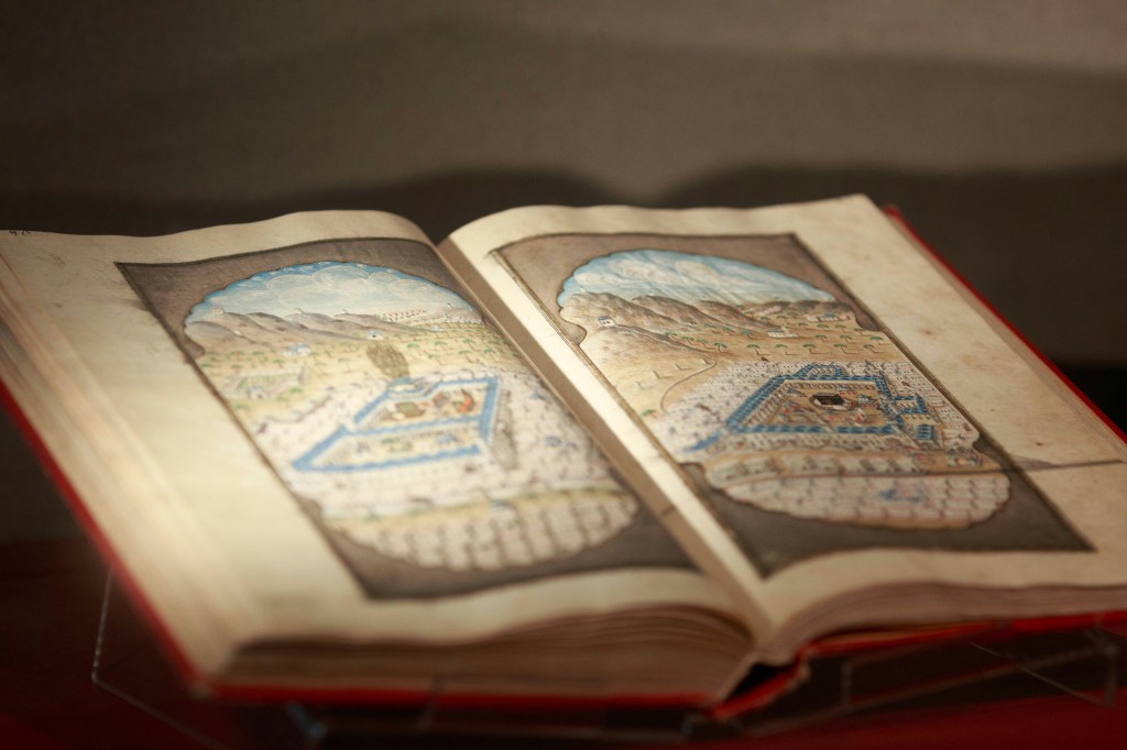 A photo of a medieval book , open, with vaguely two images one on the left, one on the right of what seams to be palaces.  