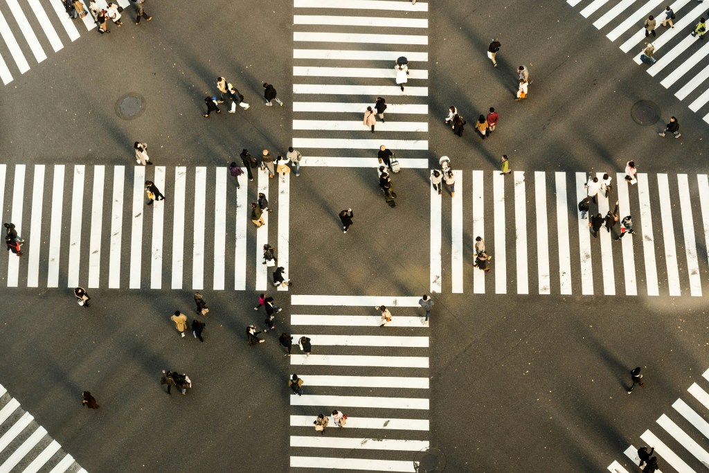 areal photo of crossraos section, with lots of zebra stripes and people crossing the road
